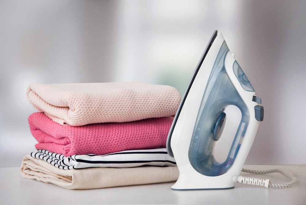 Clothes iron next to a pile of folded towels